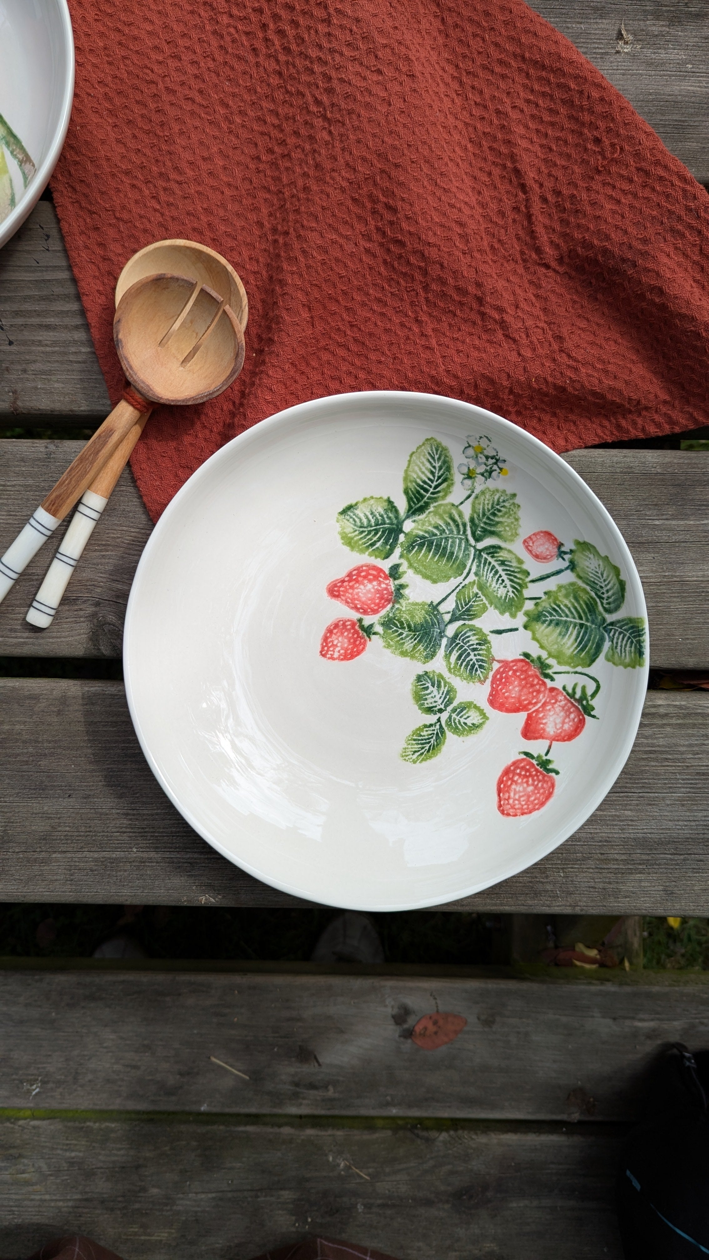 ceramic plate on a wooden picnic table with serving spoons and napkin