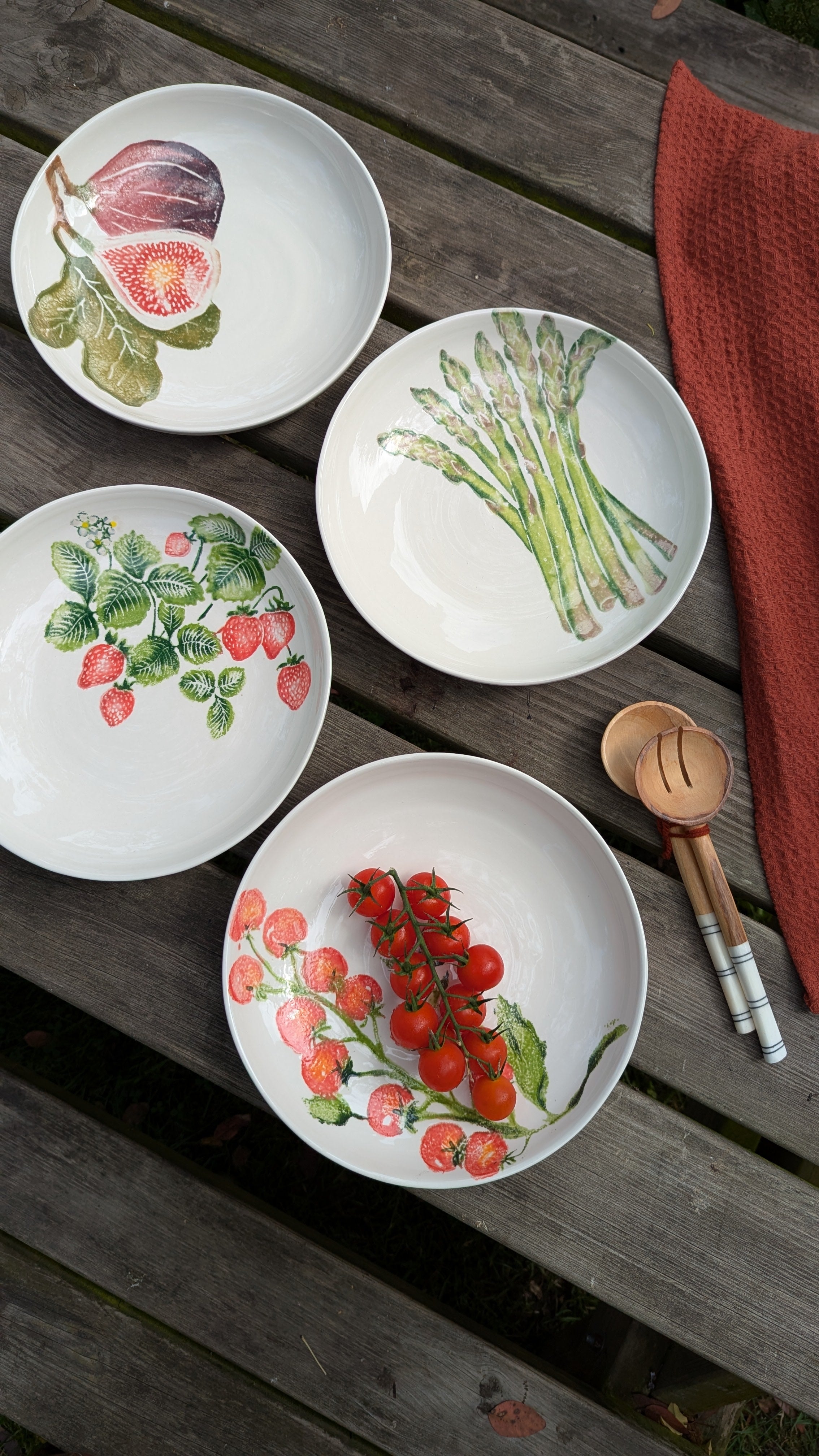 Four decorative plates on a wooden picnic table