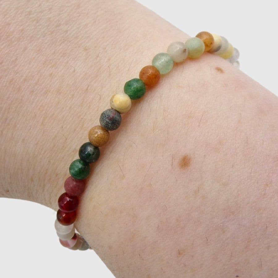 Multicolored beaded bracelet on a wrist against a white background