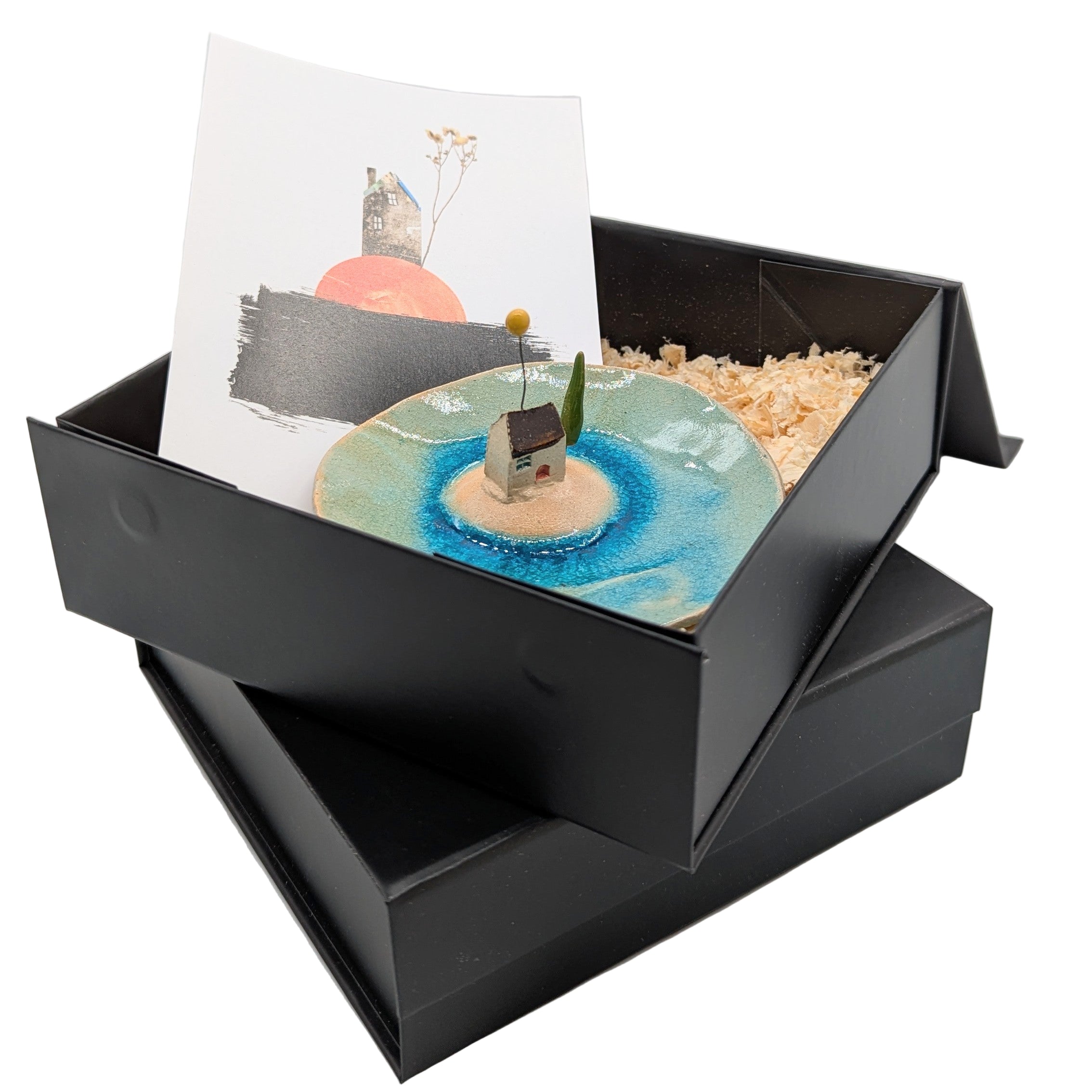 Black open box with a miniature landscape and card on a white background