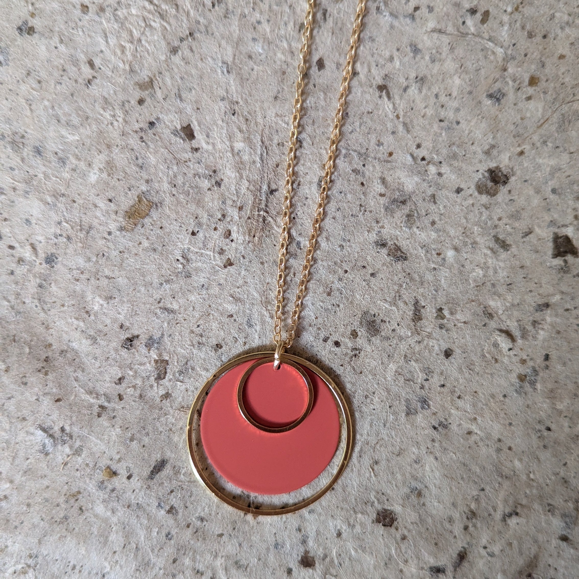 Necklace with a rust orange pendant on a textured gray surface