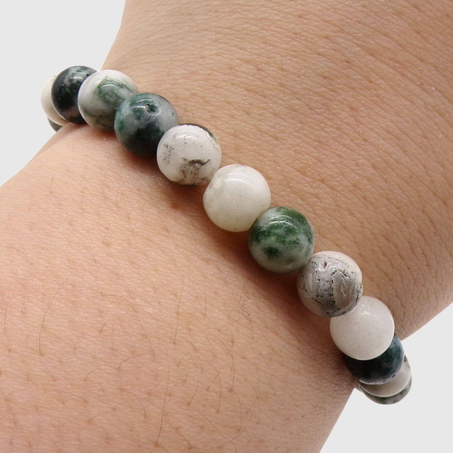 Tree Agate bracelet with green and white beads on a wrist against a neutral background