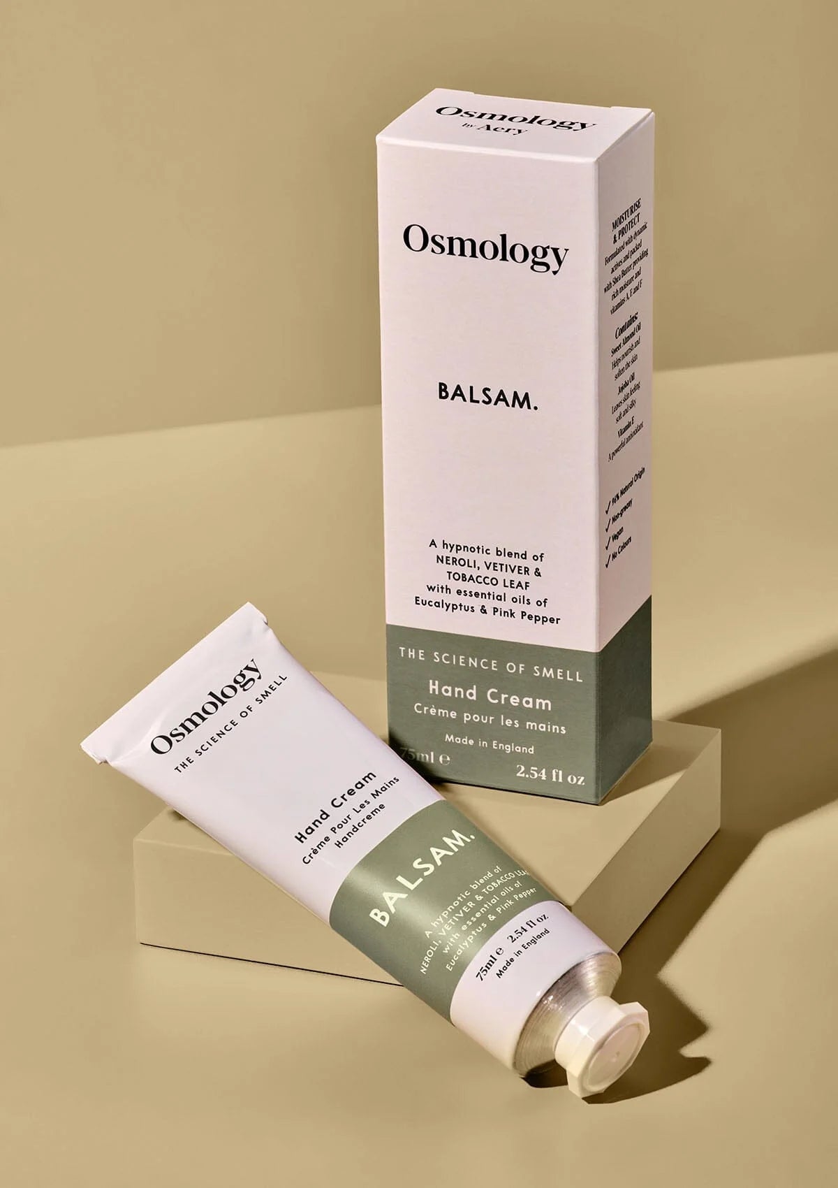 Osmology Balsam hand cream and packaging on a beige background
