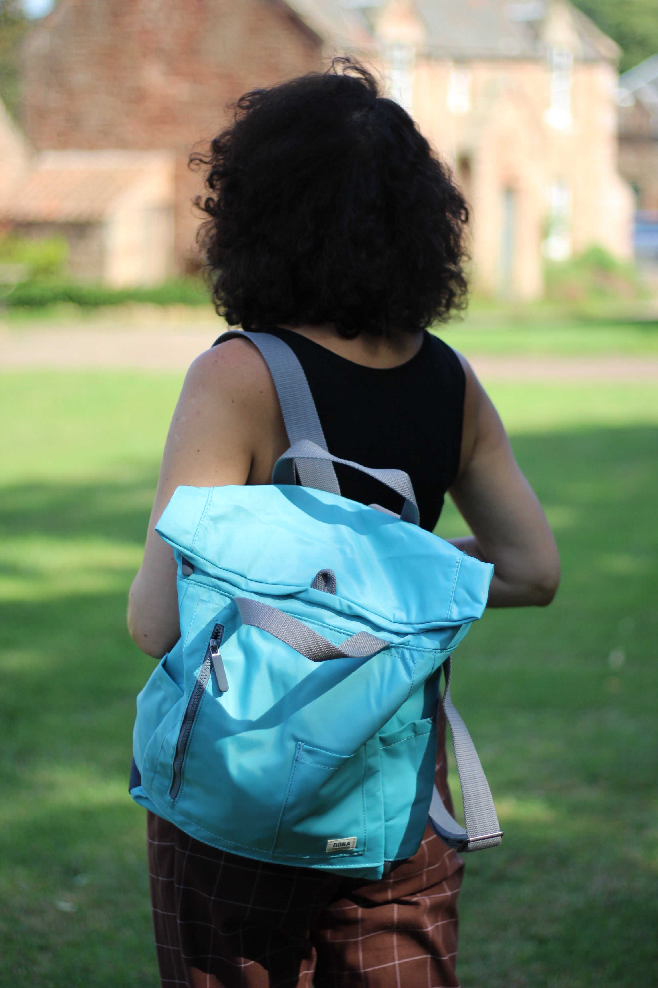 Person wearing a light blue backpack outdoors with a blurred background