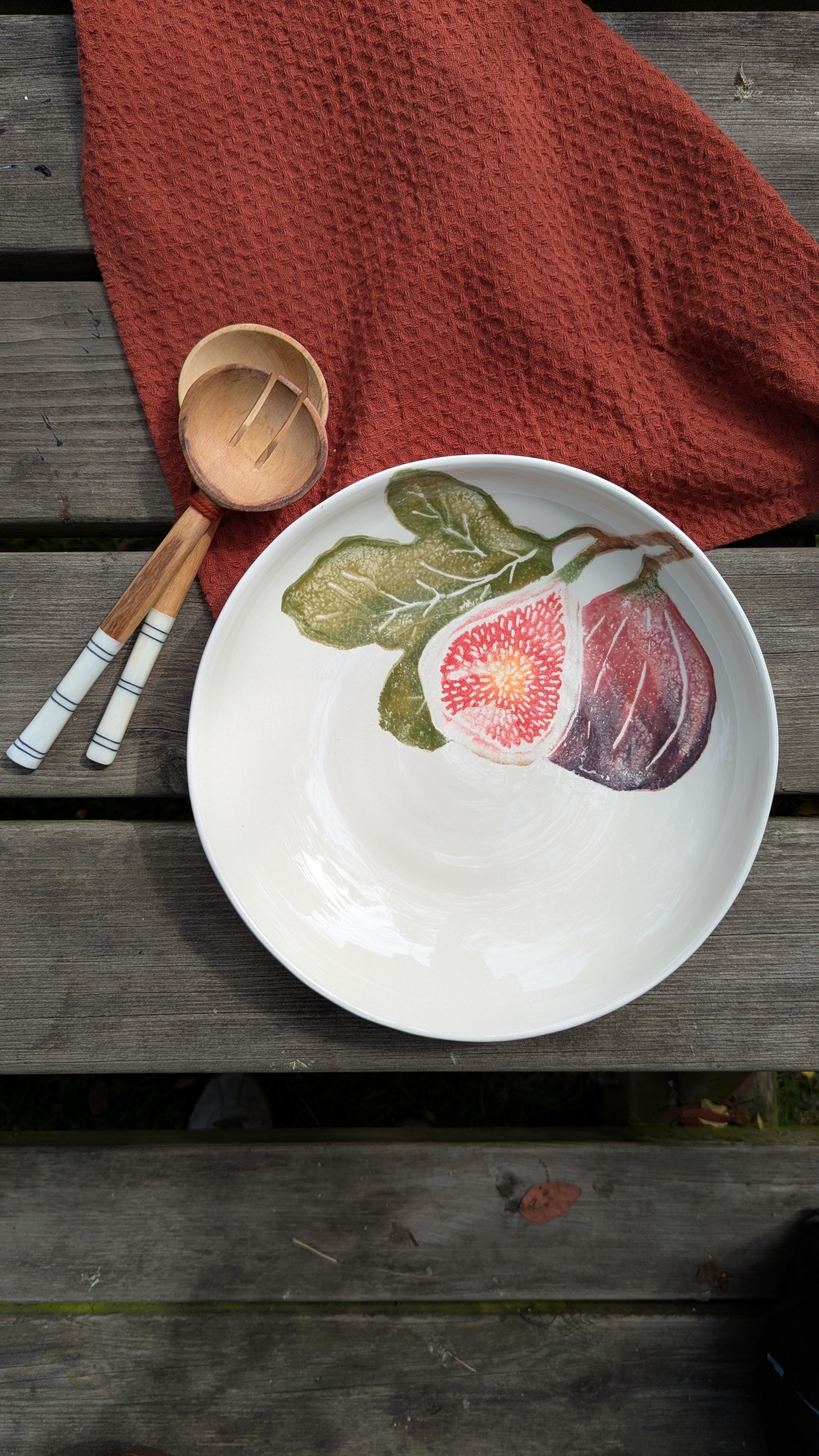White plate with fig fruit design on a wooden surface with a red cloth