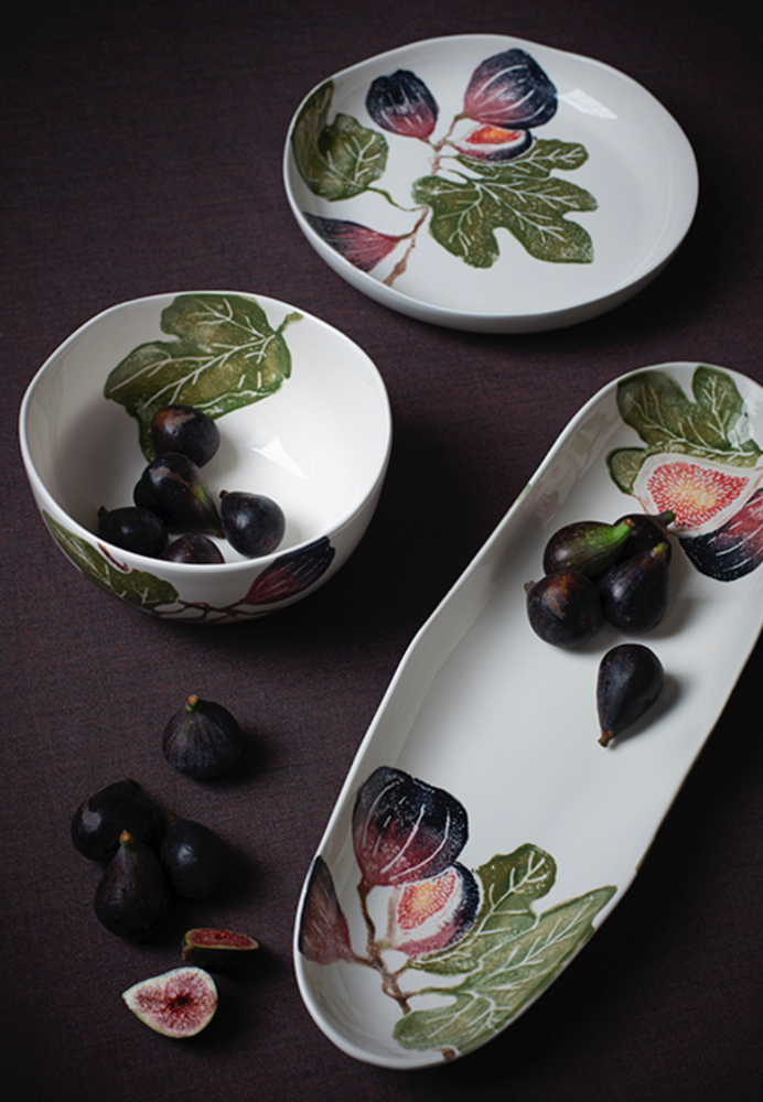 Ceramic bowls and platter with fig design on a dark surface