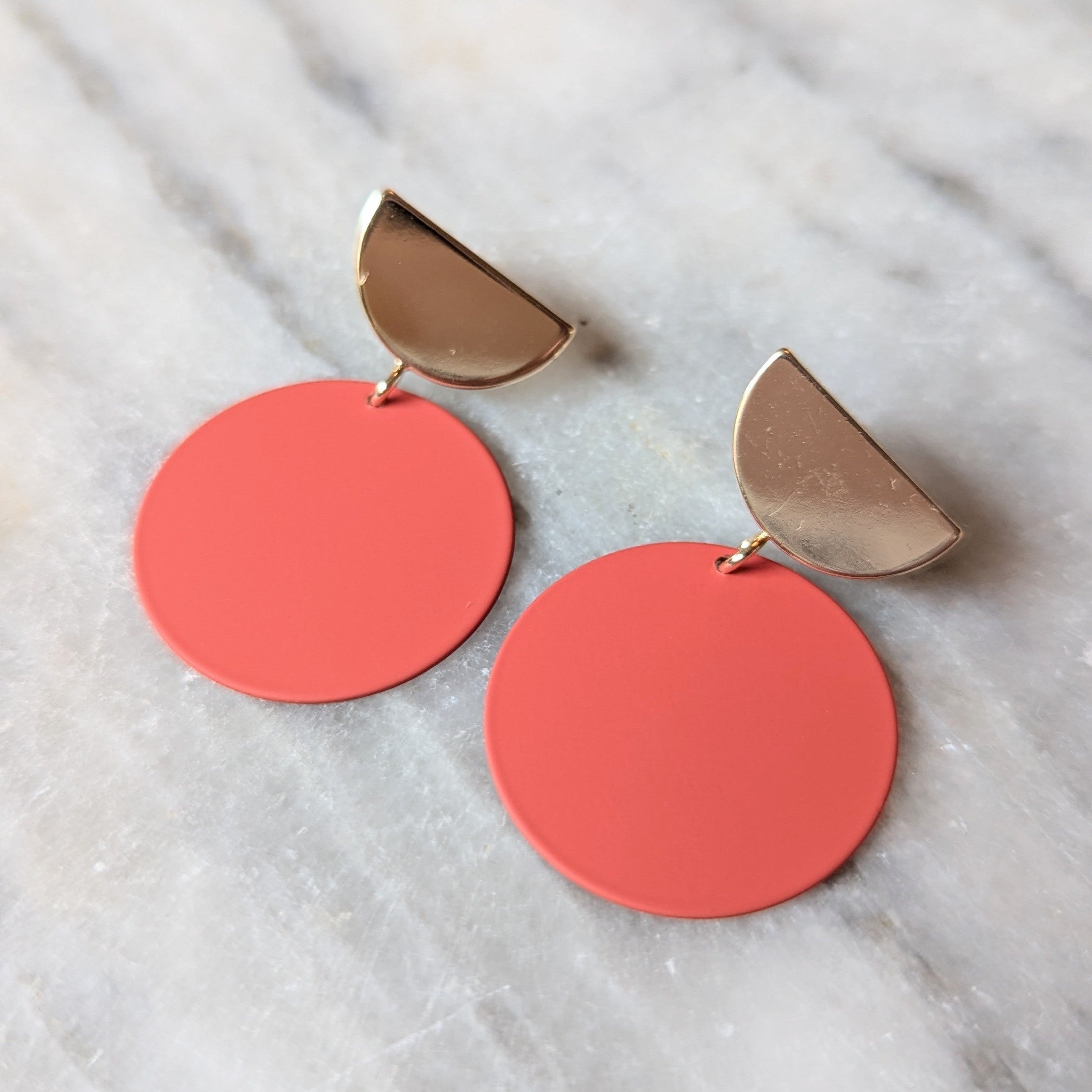 Coral earrings with gold accents on a marble surface