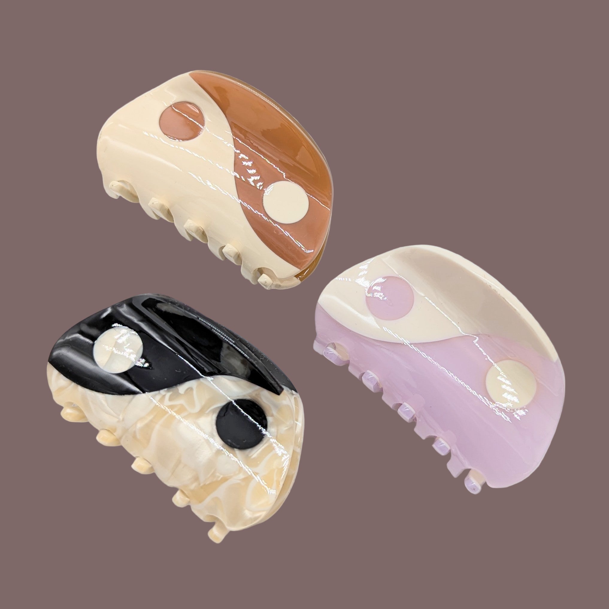 Three decorative hair clips with marble-like patterns on a white background