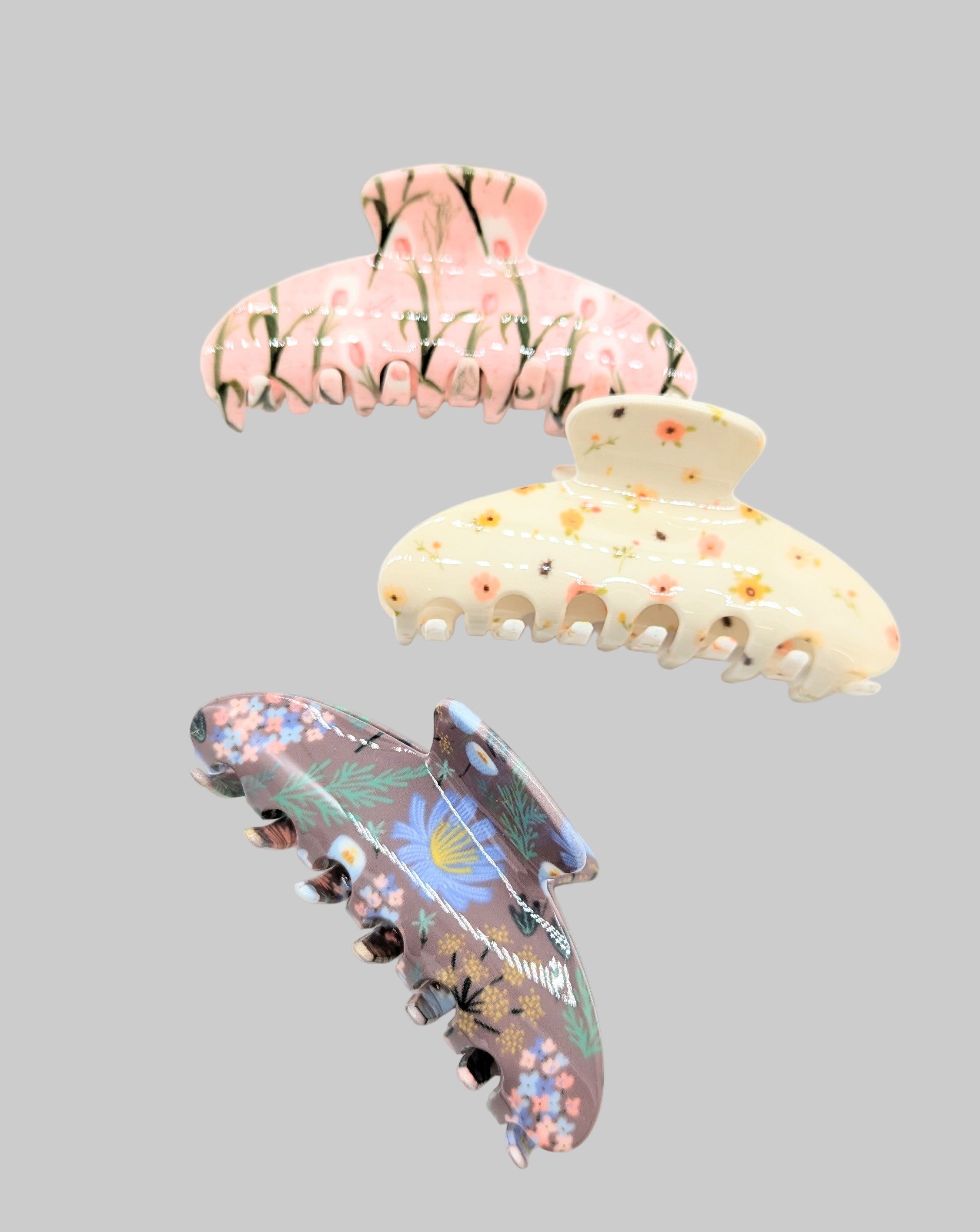 Three decorative hair clips with floral designs on a white background